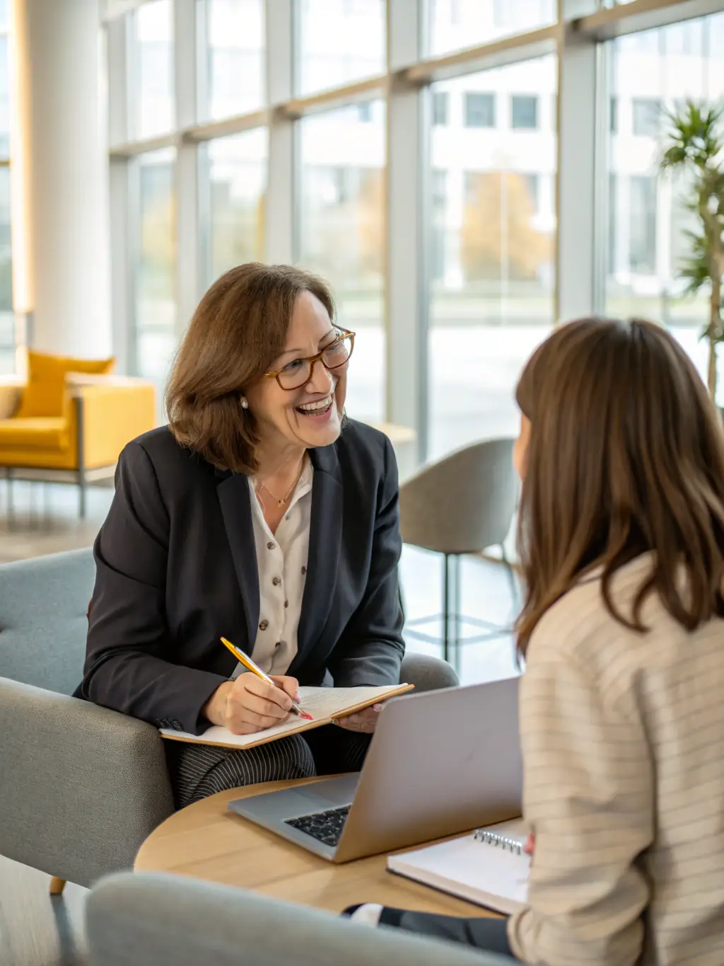 A business coach facilitating a one-on-one session with a client in a modern office setting, focusing on career development and goal setting.